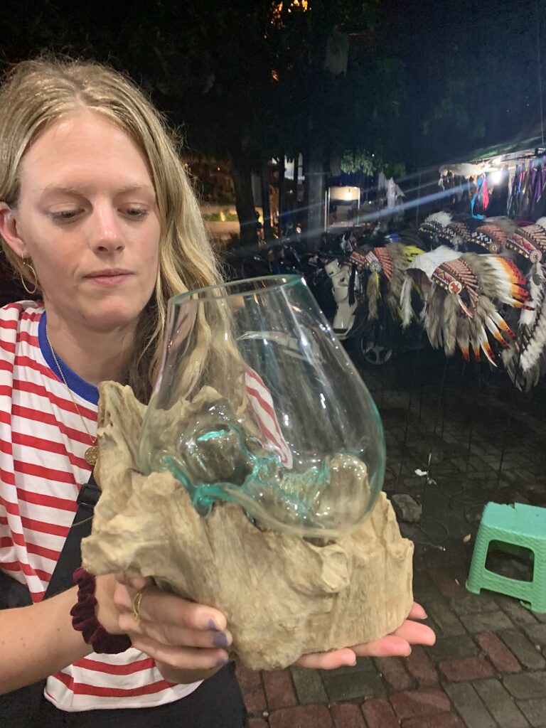 Woman holds a glass terrarium in Ubud market, Bali. Pigee 